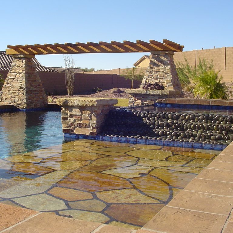 Pool with stone, stone waterfall, and stone pilars with wooden pergola